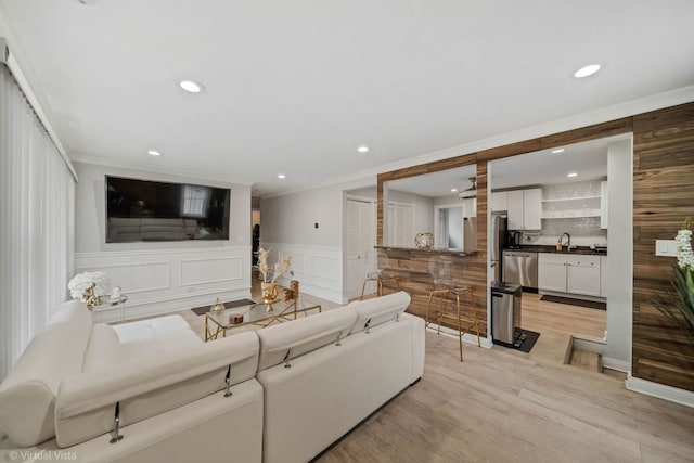 living area featuring light wood finished floors, recessed lighting, wainscoting, and ornamental molding