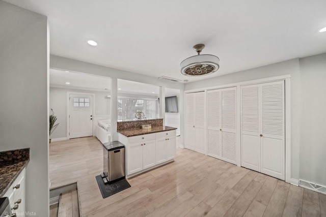 kitchen with white cabinetry, dark stone countertops, recessed lighting, and light wood finished floors