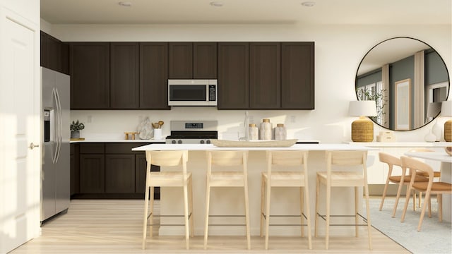 kitchen featuring dark brown cabinets, a breakfast bar area, stainless steel appliances, and light wood-style floors