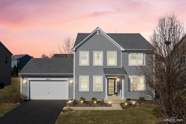 view of front facade featuring a lawn, an attached garage, driveway, and roof with shingles