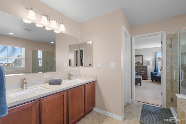 ensuite bathroom with a shower stall, double vanity, and a sink