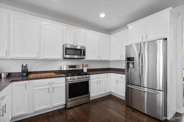 kitchen featuring dark countertops, white cabinets, appliances with stainless steel finishes, and dark wood finished floors