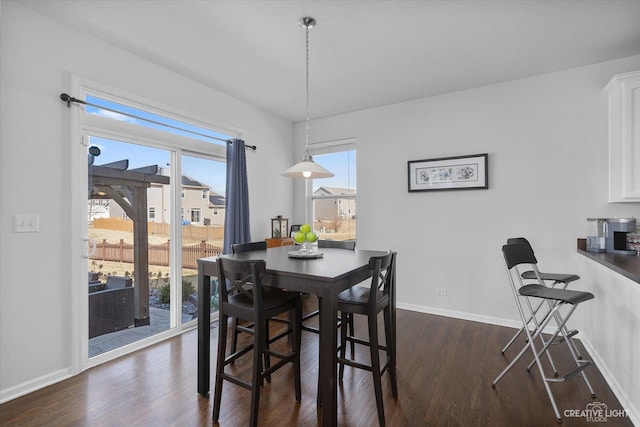 dining area with baseboards and dark wood-style flooring