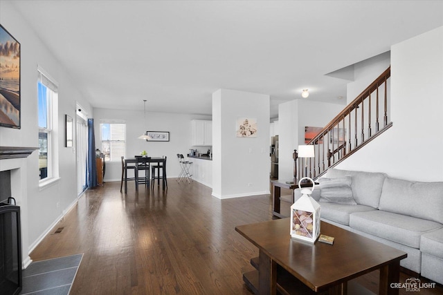 living area featuring visible vents, dark wood-style flooring, and baseboards