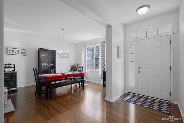 foyer entrance featuring a chandelier, visible vents, baseboards, and dark wood-style flooring