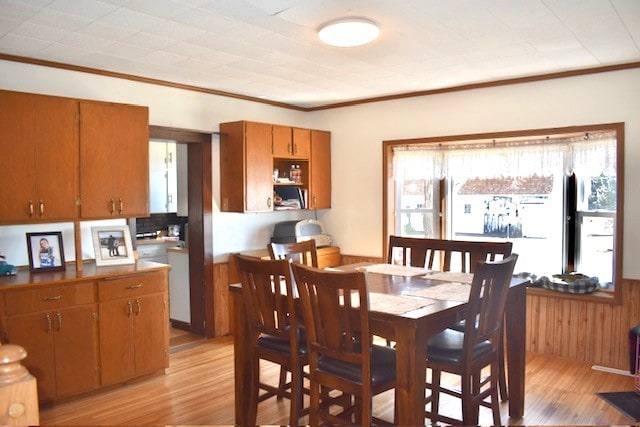 dining area with light wood finished floors and ornamental molding