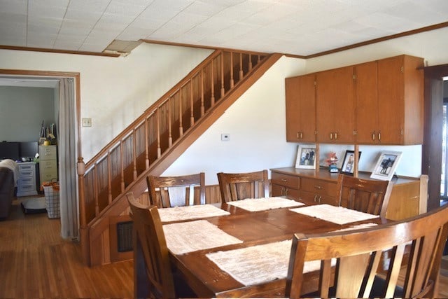 dining space with stairway, wood finished floors, and crown molding