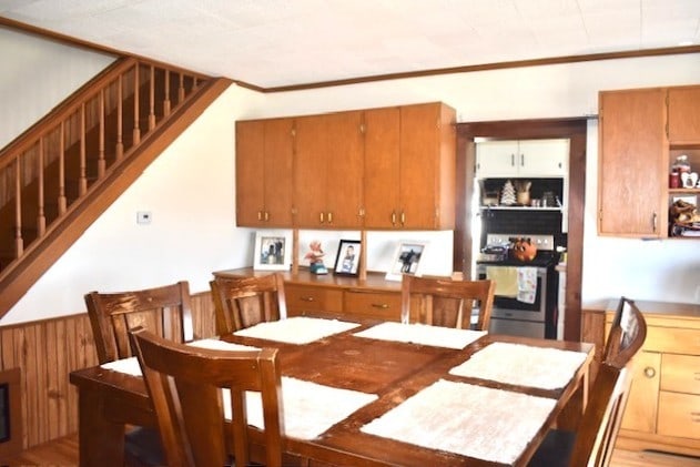 dining room with stairway, wood walls, and wainscoting