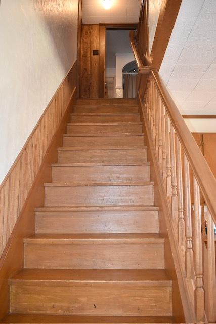 stairway with wooden walls and a wainscoted wall