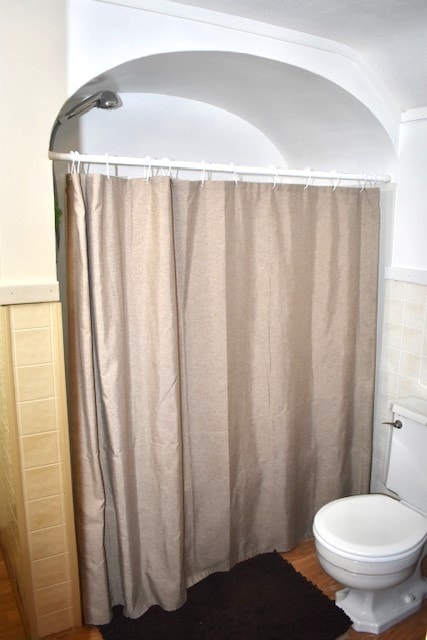 full bathroom with tile walls, toilet, and wood finished floors