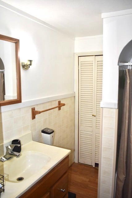 bathroom featuring vanity, tile walls, wood finished floors, and wainscoting