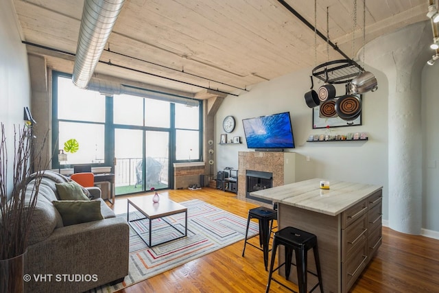 living room featuring a wall of windows, wood finished floors, and a tile fireplace