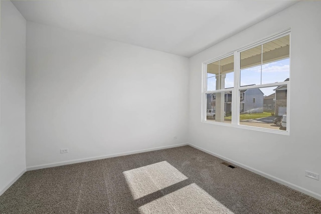 empty room featuring carpet flooring, visible vents, and baseboards