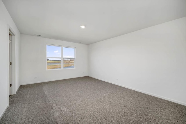 empty room featuring visible vents, carpet, and baseboards