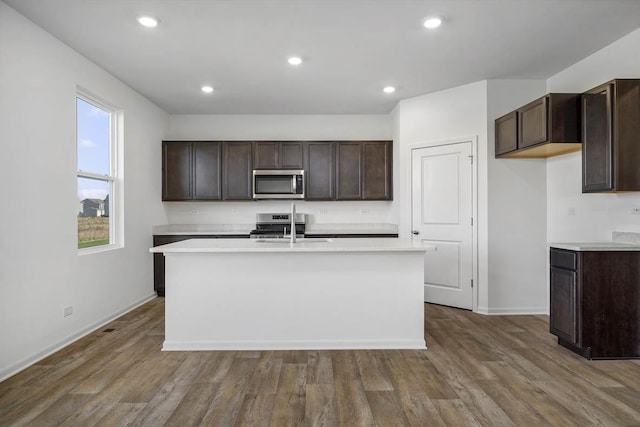 kitchen featuring light countertops, wood finished floors, dark brown cabinetry, and stainless steel appliances