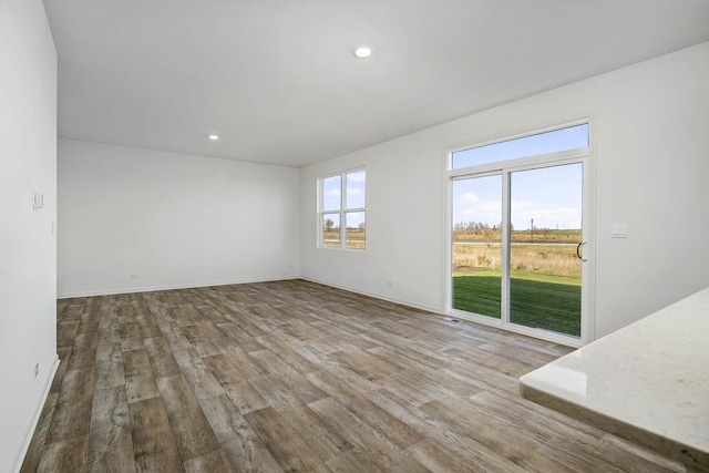 spare room featuring recessed lighting, wood finished floors, and baseboards