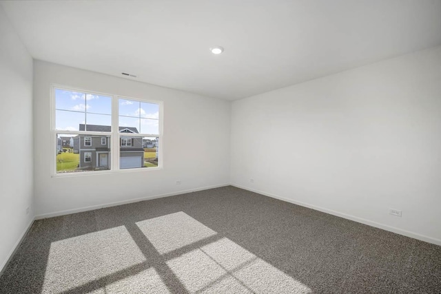 carpeted spare room with visible vents and baseboards