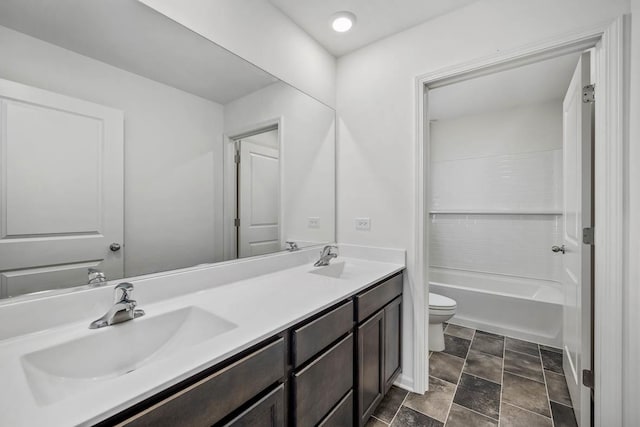 bathroom featuring double vanity, toilet, and a sink