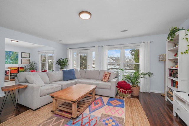 living room with visible vents, baseboards, and wood finished floors