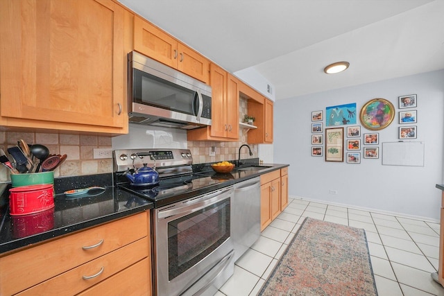 kitchen featuring dark stone countertops, light tile patterned floors, a sink, decorative backsplash, and stainless steel appliances