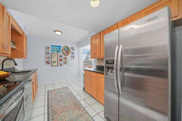 kitchen with a sink, backsplash, dark countertops, stainless steel appliances, and light tile patterned floors