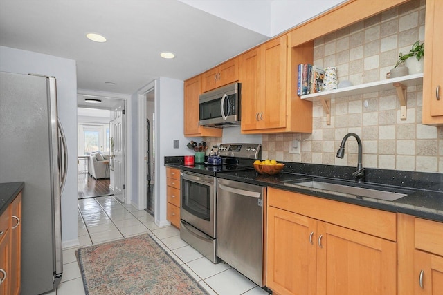 kitchen with a sink, stainless steel appliances, light tile patterned flooring, and decorative backsplash