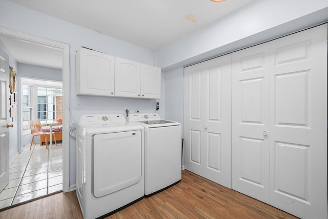 laundry area with light wood-type flooring, cabinet space, and separate washer and dryer