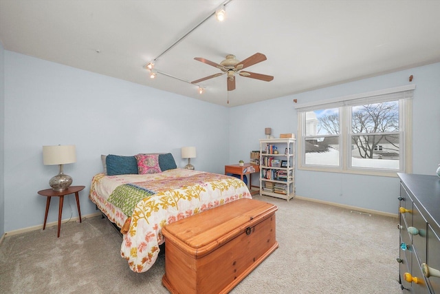 bedroom with baseboards, light colored carpet, and rail lighting