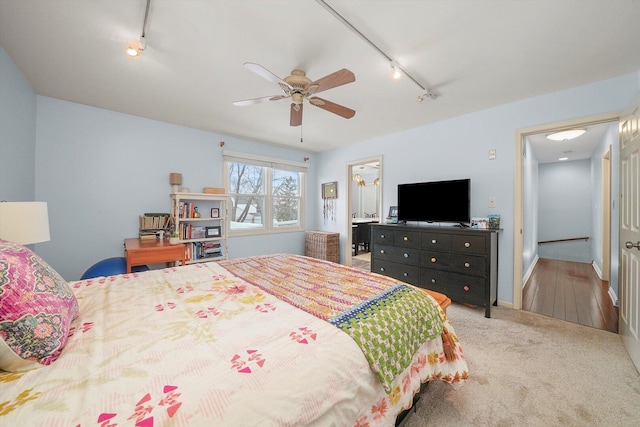 carpeted bedroom featuring baseboards, ceiling fan, and track lighting