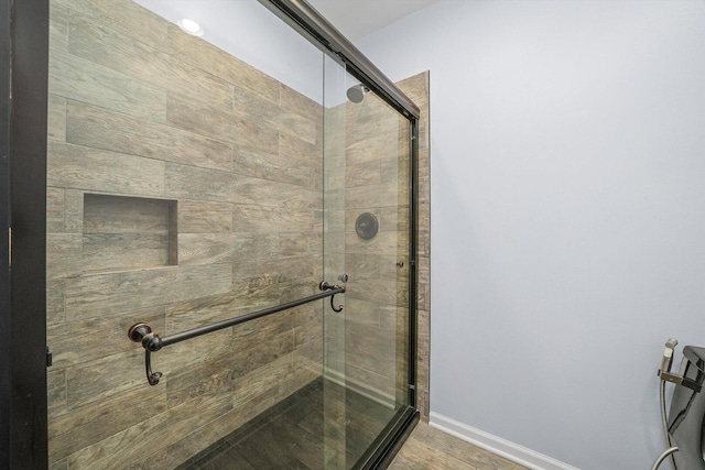 bathroom with a shower stall, wood finished floors, and baseboards