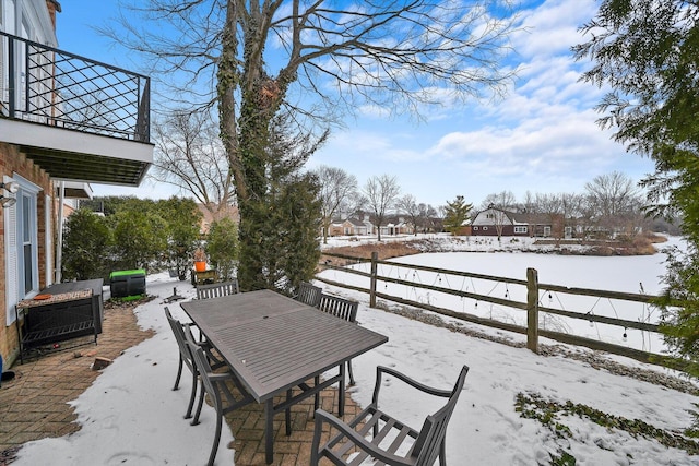 snow covered patio with outdoor dining space and fence