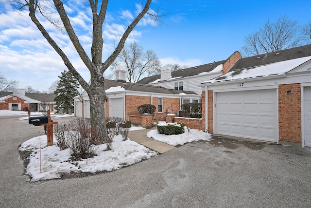 snow covered property featuring brick siding and a chimney