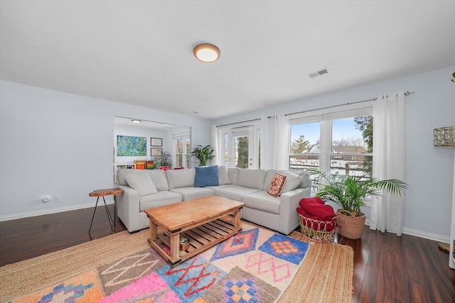 living area featuring visible vents, baseboards, and wood finished floors