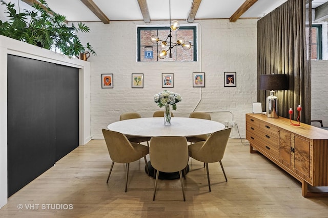 dining space featuring light wood-type flooring, beam ceiling, a chandelier, and brick wall