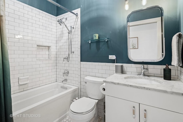 bathroom featuring toilet, vanity, wainscoting, bathtub / shower combination, and tile walls