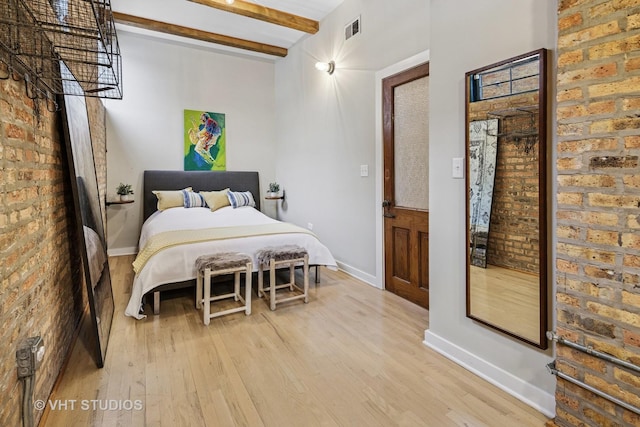 bedroom with light wood-type flooring, visible vents, beam ceiling, and brick wall