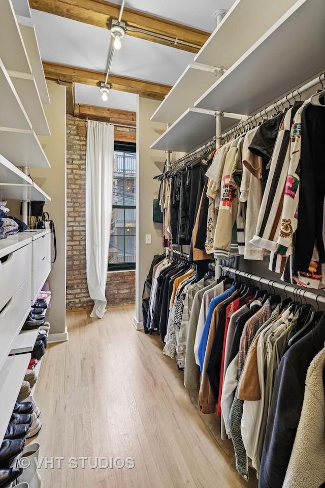 walk in closet with beamed ceiling and wood finished floors