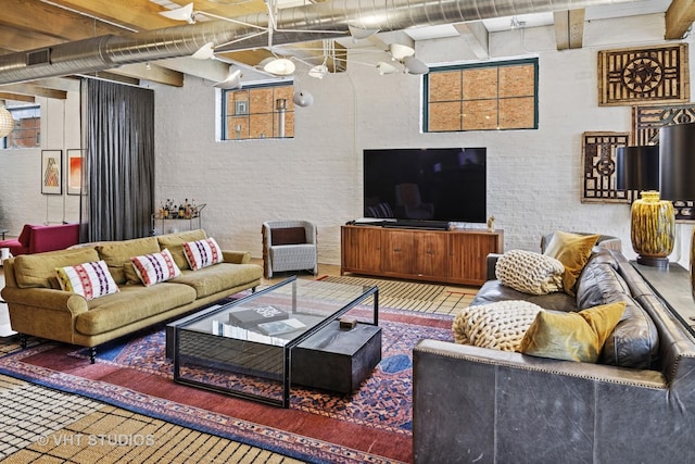 living area featuring beamed ceiling, brick wall, and a high ceiling