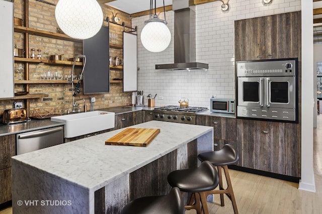 kitchen with open shelves, a sink, stainless steel appliances, light wood-style floors, and wall chimney exhaust hood