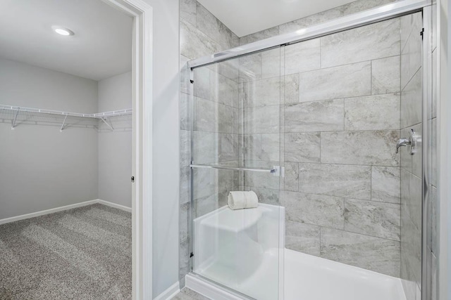 full bathroom featuring a spacious closet, baseboards, and a stall shower