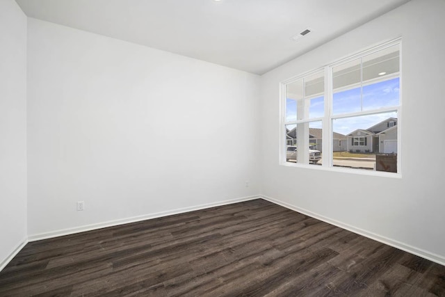 unfurnished room with visible vents, baseboards, and dark wood finished floors