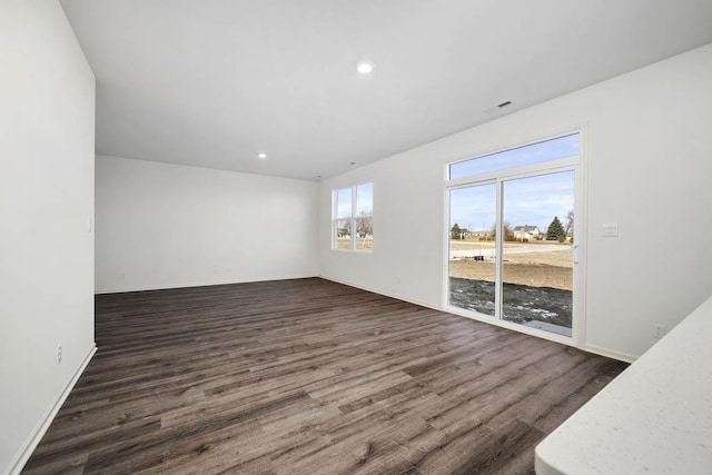 unfurnished room with recessed lighting, visible vents, baseboards, and dark wood finished floors