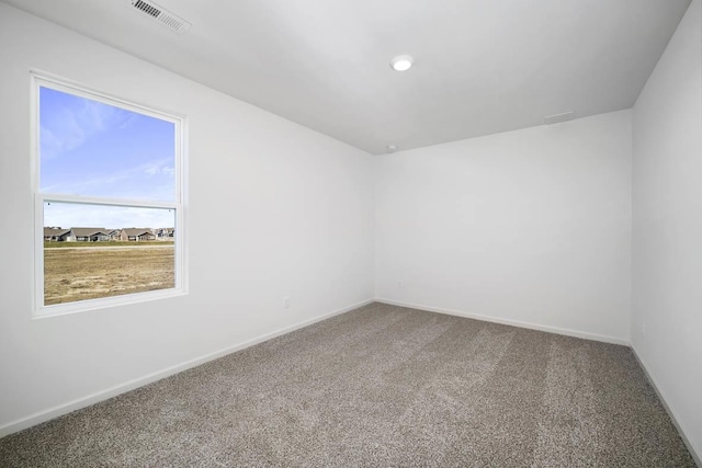 empty room featuring visible vents, carpet floors, and baseboards