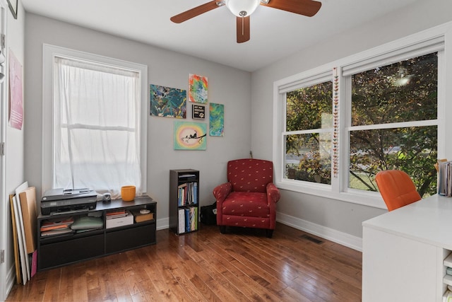 living area with visible vents, a ceiling fan, baseboards, and wood-type flooring