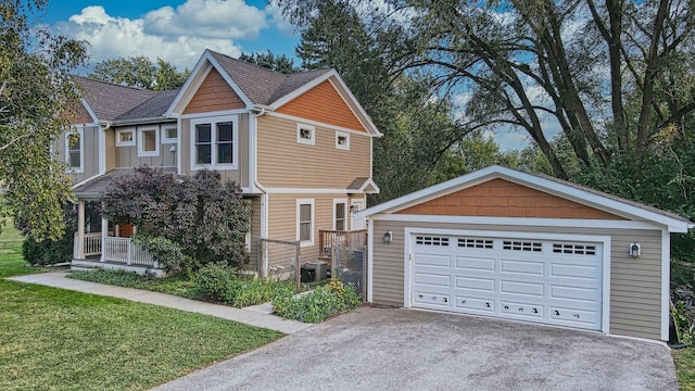 craftsman house with a detached garage, a front lawn, central AC, covered porch, and an outbuilding