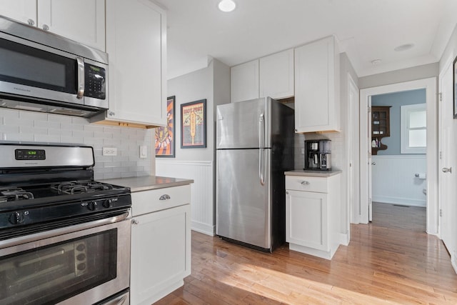 kitchen with white cabinetry, appliances with stainless steel finishes, and wainscoting