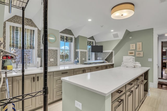 kitchen featuring lofted ceiling, light countertops, tasteful backsplash, and a sink