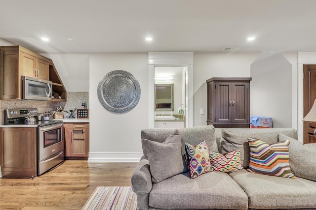 living room with light wood-style flooring, recessed lighting, visible vents, and baseboards