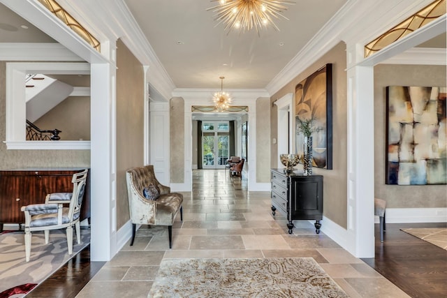 entrance foyer featuring crown molding, stone tile flooring, baseboards, and a chandelier