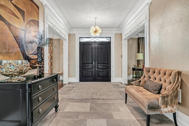 entryway featuring a notable chandelier, stone finish floor, baseboards, and ornamental molding